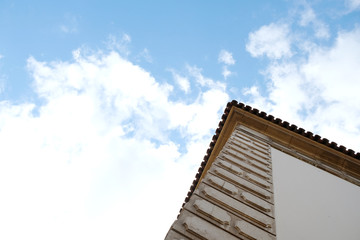 Fototapeta na wymiar Corner of a building and sky and clouds above it. Architecture detail with copy space.