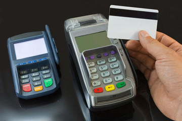 A male hand holds a payment card above the payment terminal.