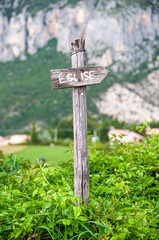 Wooden sign indicating the direction of the church in a village in France