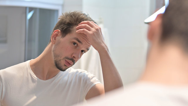 Young Man Fixing Hair In Mirror