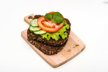Vegetarian sandwich with lettuce, tomato, cucumber and parsley, on a white background