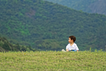 Naklejka na ściany i meble A little boy sitting on the grass