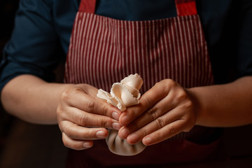 The process of cooking khinkali - dishes of Caucasian cuisine. Woman preparing meat dish (national georgian cuisine Khinkali). Woman sculpts khinkali, close-up of hands