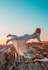 Lifestyle, a levitating woman in a white dress with black dots on a sunset