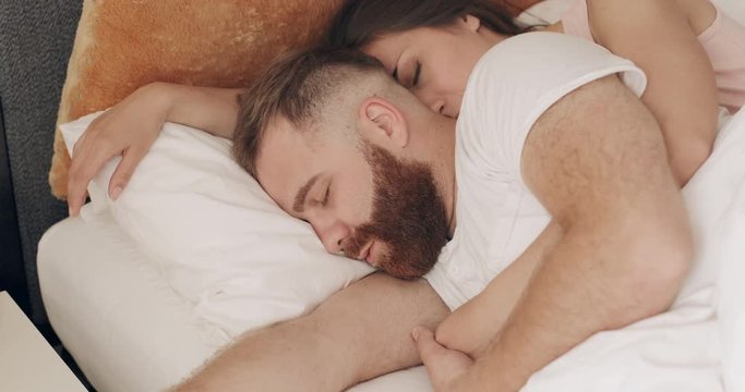 Close up view of cute loving couple hugging in bed while sleeping in early morning. Young woman embracing man while lying on bed and dreaming .Concept of lifestyle and relationship.