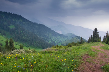  evening in the mountain, road on the ridge and rain over the city Almaty