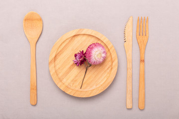 Zero waste, plastic free concept. Wooden plate, glass cup, Set of bamboo cutlery. Flat lay on textile linen background