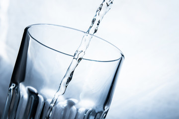 pouring lemonade drink into a transparent glass on a white background