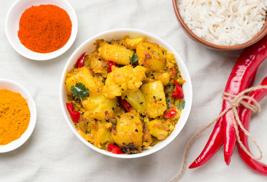 Gobi aloo indian vegetarian vegetable dish in bowl next to ingredients
