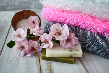 Obraz na płótnie Canvas Handmade gray, pink and white washcloths with soap, pink apple tree flowers and bath salt. Relax at home