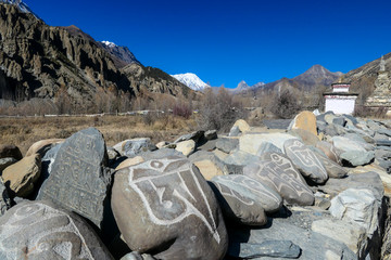Manang/Nepal - 10 30 2018: A trail in high parts of Himalayas. Pile of stones shaping a wall. Some...