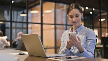Young Woman Using Smartphone and Laptop
