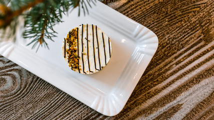 Circular creamy cake with chocolate stripes on a wooden table.