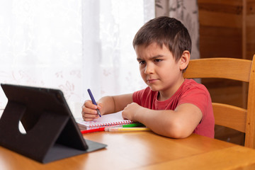 5 years old child studying from home. preschool kids with computer. online remote learning with digital notebook and doing school homework