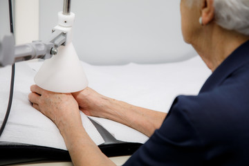Physiotherapy device treats arthritis and arthrosis, on the hands of an elderly lady