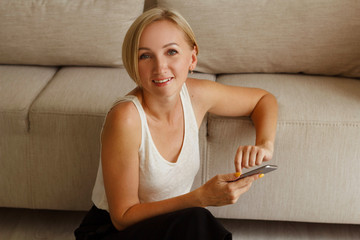 Young pretty blond woman freelancer working from home using smartphone
