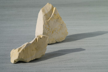 Shattered white clay on the cyan background. Close up. Ural food clay. No people..There is noise...