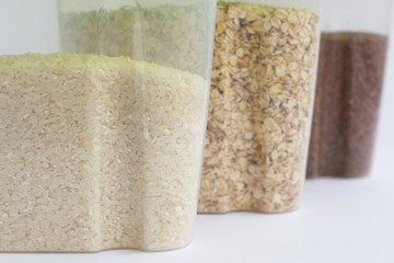 various cereals in containers or jars on a white background