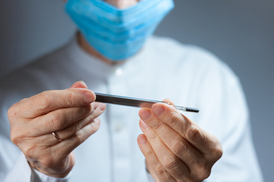 Coronavirus quarantine and Air pollution pm2.5 concept. Old sick woman wearing respirator mask for protect holds thermometer. Wuhan, China epidemic virus symptoms background.