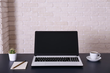 Creative workspace of a blogger. White laptop computer on wooden table in loft style office with brick walls. Designer's table concept. Close up, copy space, background.