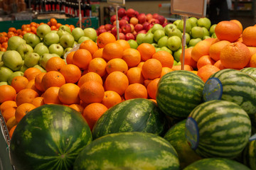 oranges, watermelons and apples on the counter in the store