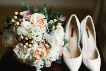 Brides wedding shoes with a bouquet with roses and other flowers