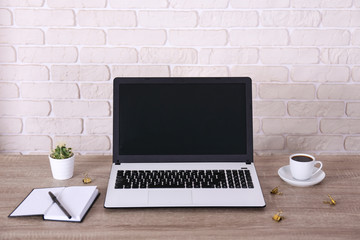 Creative workspace of a blogger. White laptop computer on wooden table in loft style office with brick walls. Designer's table concept. Close up, copy space, background.
