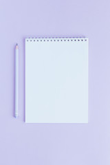 Notebook with blank page and pencil on a violet background.