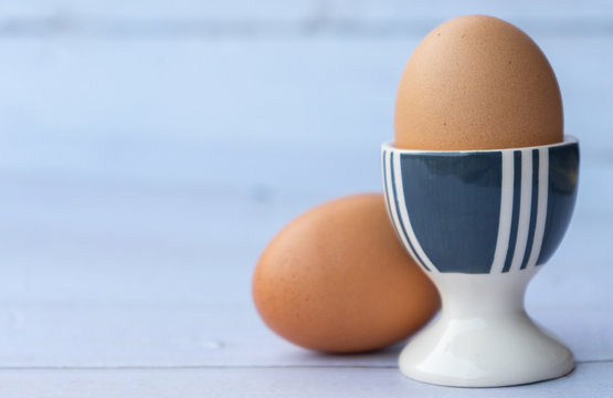 Egg served on porcelain egg holder on the wooden table with copy space.
