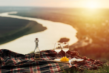 Romantic picnic in nature with panoramic background. The beauty of the setting sun, fresh fruits,...
