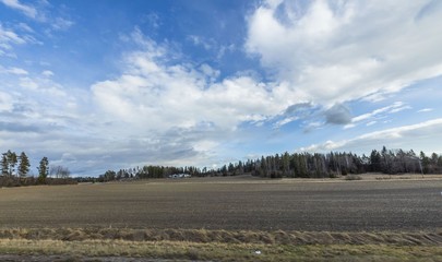Beautiful nature landscape view on spring day. Plowed field merging with blue sky and white clouds....