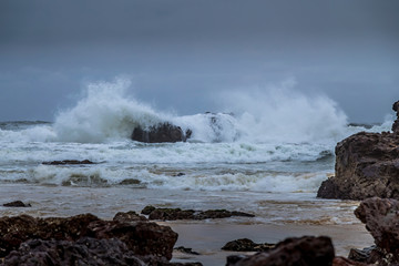 Rocks next to the beach of the Camel Rock bay in New South Wales, Australia at a cloudy and windy day in summer with strong waves in the ocean. 