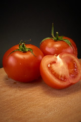 Red tomato, black board, black background.