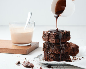 chocolate brownie with chocolate syrup and coffee on a white background