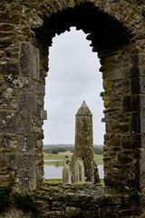McCarthy's Tower seen through a cathedral window in the medieval monastery of Clonmacnoise, during a rainy summer day.