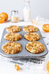 Close-up of orange muffins in a pan with streusel, on white table, copy space
