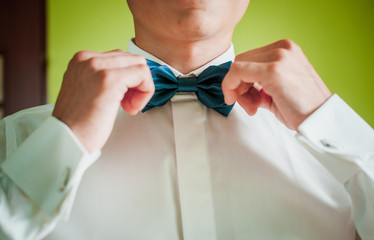 Groom hold green bowtie on the neck