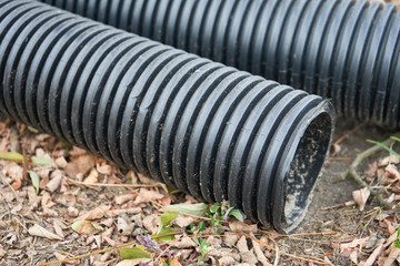 corrugated pipe closeup,black sewer pipes lie in the fall on the ground