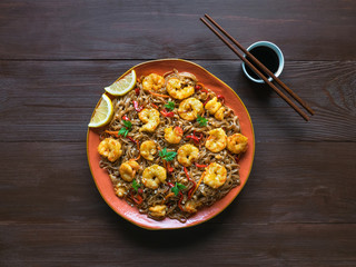 Asian food udon noodles with fried shrimps, sesame and pepper close-up on a plate