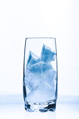 Ein Glas mit blauen Eiswürfeln vor einem weißen Hintergrund
