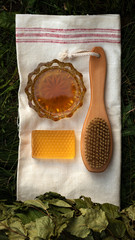 Bath soap lies on a light towel. A birch broom, a body brush and natural honey lie nearby. Set of...