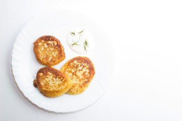 Dish of fried curd pancakes on a white plate on a white background