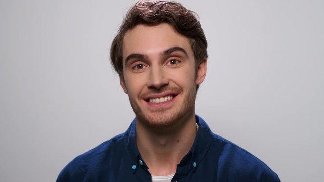 Man waving head yes at camera. Male model smiling on light background