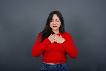 Faithful woman closes eyes and keeps hands on chest near heart, shows her kindness or favour,...