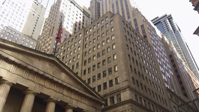 Vertical movement of the camera showing the outside facade of a museum building with a bronze sculpture in front and skyscrapers at the back