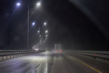 Night highway with cars, lights and rain