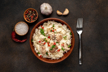 Homemade pilaf with meat and spices in a bowl on a stone table. Eastern cuisine.