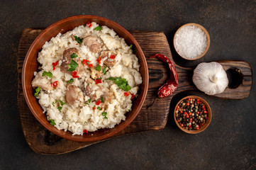Homemade pilaf with meat and spices in a bowl on a stone table. Eastern cuisine.
