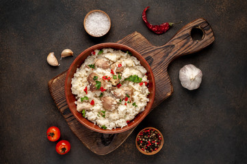 Homemade pilaf with meat and spices in a bowl on a stone table. Eastern cuisine.