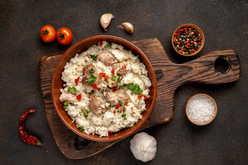 Homemade pilaf with meat and spices in a bowl on a stone table. Eastern cuisine.